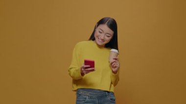 Akıllı telefon kullanan ve elinde kahve tutan sıradan bir yetişkin.