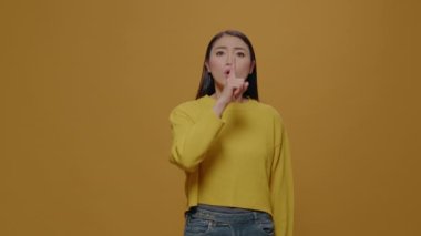 Gizli kişi kamerada sessizlik işareti gösteriyor.