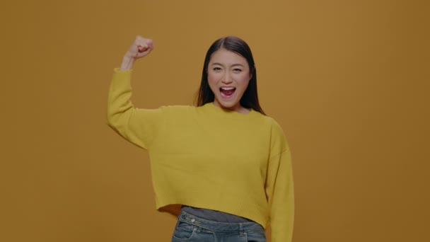Athletic woman flexing arms muscles over yellow background — Αρχείο Βίντεο