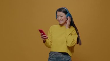 Stüdyoda müzik dinleyip şarkı söyleyen Asyalı kadın.