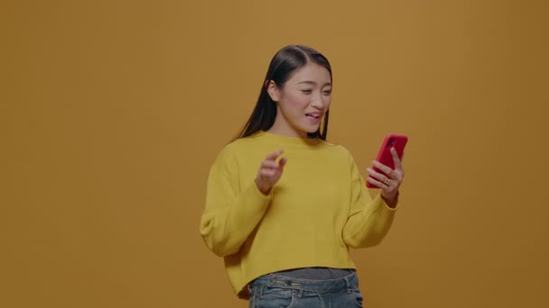 Iloinen nainen vilkuttaa videopuhelu älypuhelimeen studiossa — kuvapankkivideo