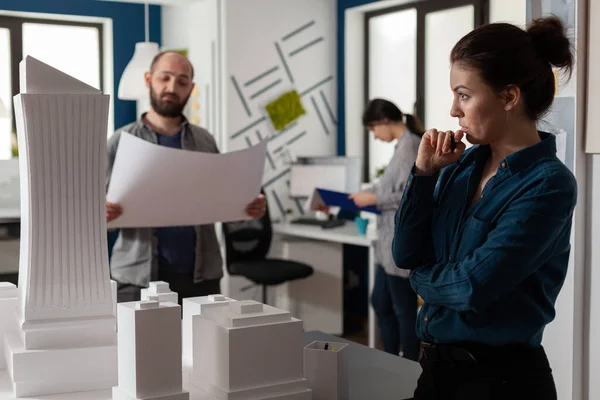 Arkitekt tittar på avståndet blickar på skyskrapa skala modell med team kollega — Stockfoto
