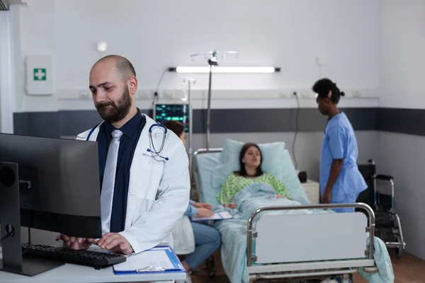 Medical doctor using personal computer to complete patient admission chart — Stok fotoğraf
