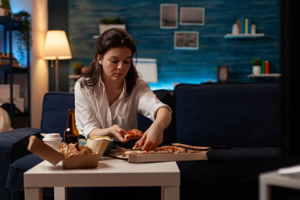 Büroangestellte zu Hause beim Abendessen und holt eine heiße Pizzascheibe aus Pappschachtel — Stockfoto