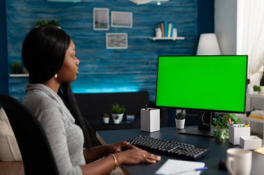 Young adult looking at computer with horizontal green screen