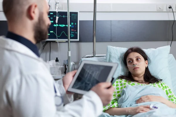 Mulher recebendo oxigênio e tendo os sinais vitais monitorados após a intervenção cirúrgica olhando para o médico com ressonância magnética — Fotografia de Stock