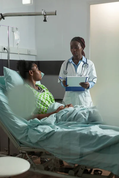 Medico terapista afroamericano che spiega le competenze mediche al paziente malato durante la consultazione medica — Foto Stock