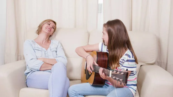 年轻的吉他手小孩坐在妈妈旁边的沙发上 — 图库照片