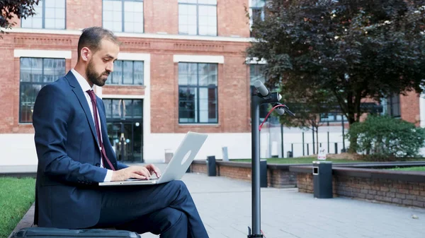 Geschäftsmann im Diplomatenanzug sitzt auf Bank vor Startup-Baubüro — Stockfoto