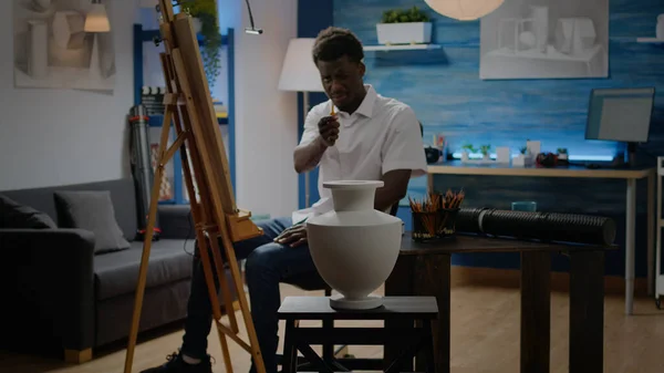 Митець афроамериканської етнічної приналежності аналізує вазу. — стокове фото