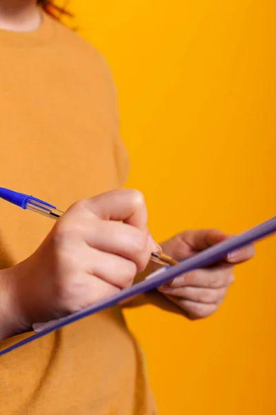 Close up of hand holding pen and writing on clipboard papers — Stock Fotó