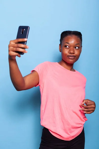 Portrait of african american young woman holding smartphone taking photo smiling at camera — Stock Photo, Image