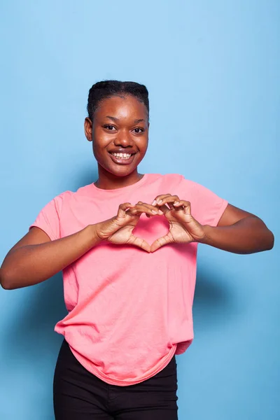 Retrato de estudante afro-americano sorrindo para a câmera fazendo símbolo de forma de coração — Fotografia de Stock