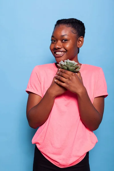 Портрет афроамериканського підлітка, який тримає квітковий горщик посміхається перед камерою. — стокове фото