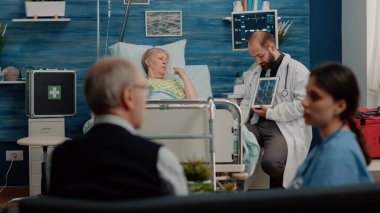 Hastalıklı emekli bir hasta röntgen taramasıyla tablete bakıyor.