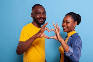 Mutlu çift kameranın önünde kalp şeklinde işaret veriyor.