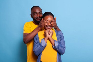 Büyük bir sürpriz hazırlamak için kız arkadaşının gözlerini kapayan neşeli bir adam.