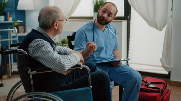 Asistente médico consultando anciano con discapacidad —  Fotos de Stock