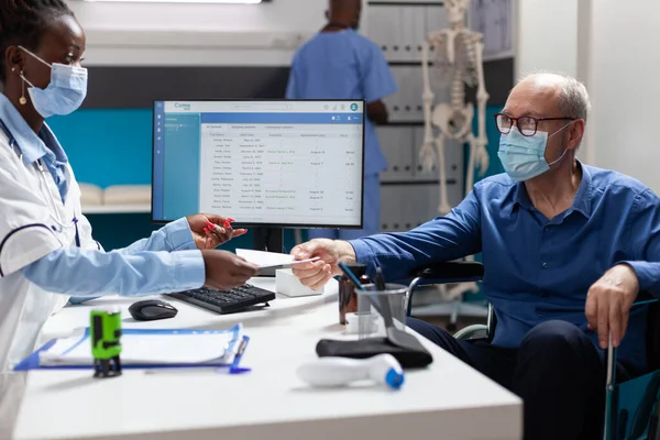 Physician doctor with face mask against covid19 stamping medication prescription — Stock Photo, Image