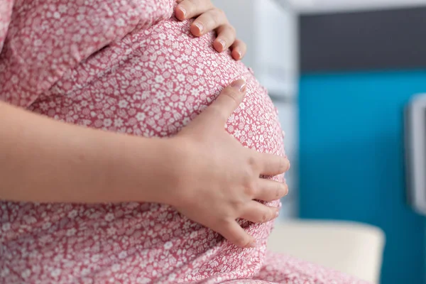 Hamile bir kadının bebek yumruğuyla el ele tutuşmasına yakın durun. — Stok fotoğraf