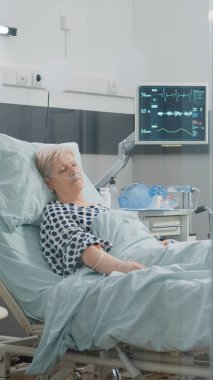 Hasta uyurken kalp atış hızı monitörüne bakan tıbbi asistan.