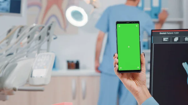 Close up de dentista segurando smartphone com tela verde — Fotografia de Stock