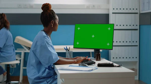 Nurse working with keyboard and horizontal green screen — Stock Photo, Image