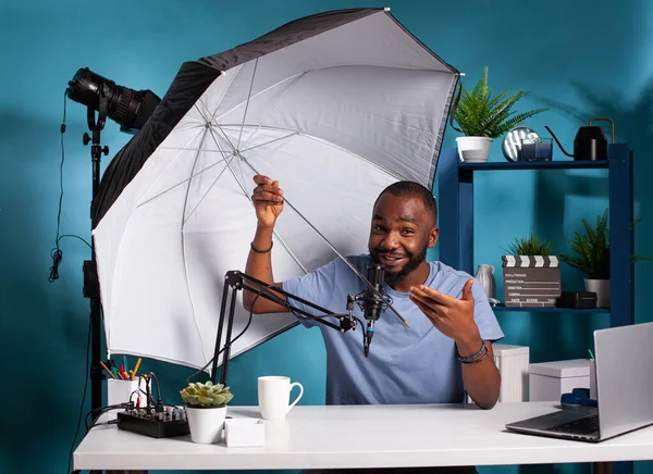 Fotógrafo profesional vlogger revisando paraguas reflector flash que presenta tamaño y beneficios — Foto de Stock