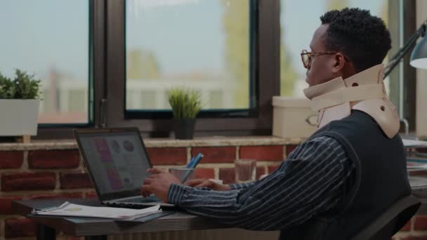 Sérült munkavállaló nyakörvvel laptoppal a finanszírozás tervezéséhez — Stock videók