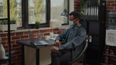 Görüntülü iletişim kullanarak yüz maskesi takan bir çalışan