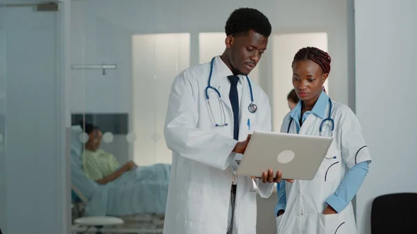 Médicos afro-americanos olhando para laptop para encontrar tratamento — Fotografia de Stock