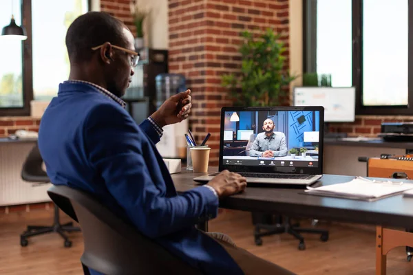 Employé de l'entreprise utilisant la vidéoconférence sur ordinateur portable pour discuter avec l'homme dans le bureau de démarrage — Photo