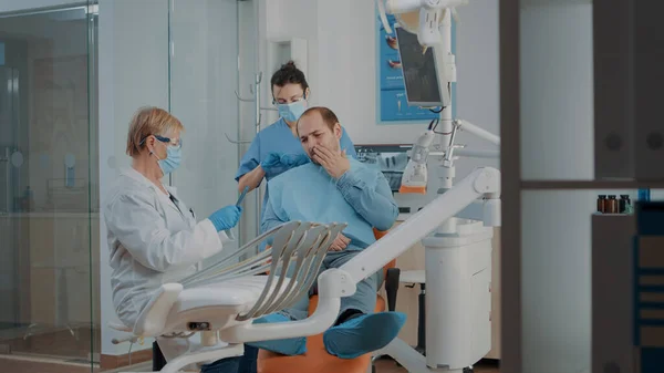 歯のX線を見て歯痛のある患者を診察する歯科医 — ストック写真
