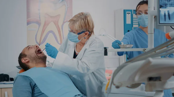 Munvårdande läkare med hjälp av tandvårdsverktyg för att göra tandundersökning — Stockfoto