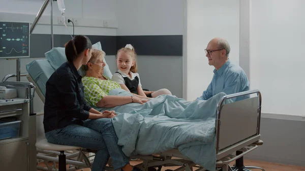 Nichtje knuffelen zieke vrouw bij familiebezoek in ziekenhuis afdeling — Stockfoto