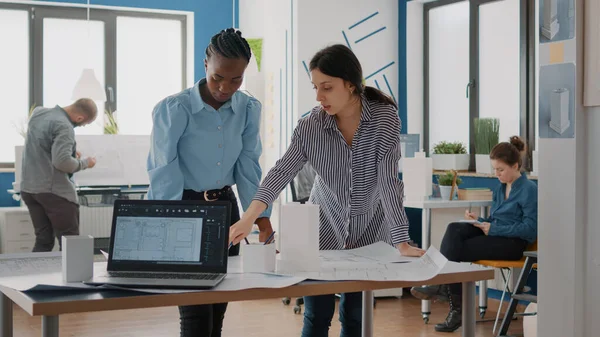 Équipe de compagnons de travail à la recherche d'un modèle de construction et des plans sur la table — Photo