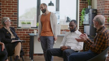 Bağımlılığın ilerlemesini kutlayan neşeli bir adam. A.A. grup toplantısında insanlar alkışlıyor.