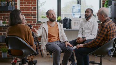 A.A. toplantısında terapi sürecini kutlamak için alkışlayan insanlarla tokalaşan bir adam.