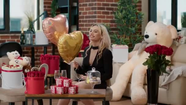 Lachende mooie vrouw op Valentijnsdag met helium hartvormige ballonnen in een kamer vol luxe cadeaus — Stockvideo