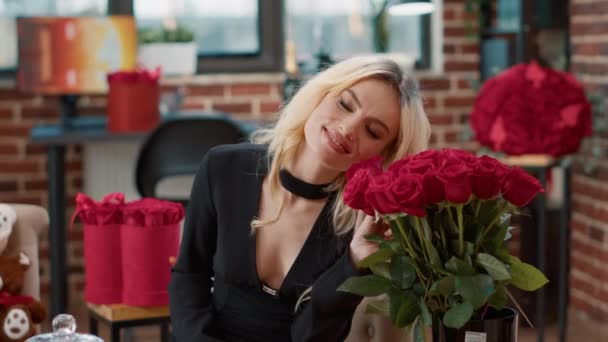 Lächelnde schöne Frau, die sich am Valentinstag geliebt fühlt und elegante Rosensträuße riecht — Stockvideo