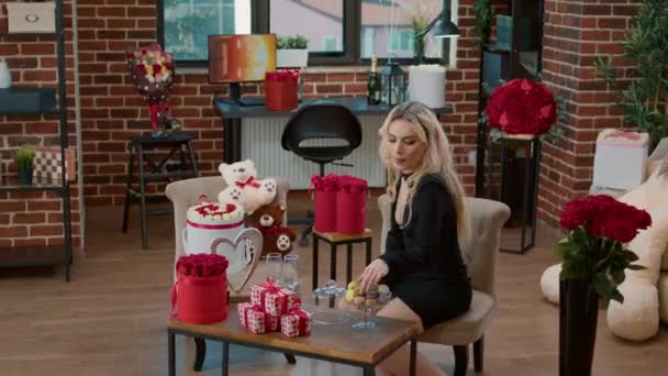 Beautiful woman eating macarons sitting at coffee table with surprise valentine gifts — Stock Video