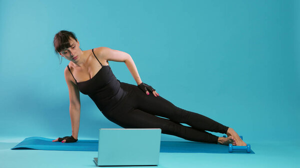 Active person doing physical exercise with online workout on laptop