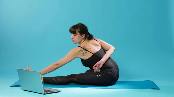 Adatto donna facendo esercizio di stretching e guardando video di meditazione — Foto Stock