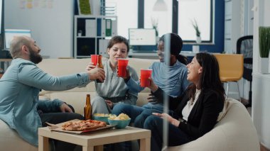 Çok ırklı bir grup insan bardak ve şişe tokuşturuyor.