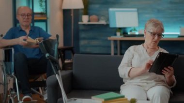 Emekli kadın evdeki dijital tablette internette geziniyor.