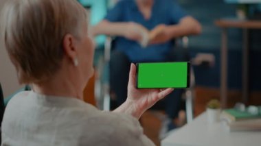 Kadın emekli cep telefonunda yatay yeşil ekrana bakıyor