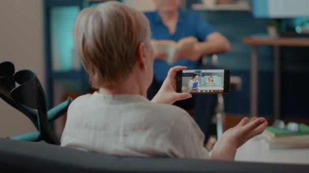 Старуха с костылями с помощью видеозвонка на мобильный телефон — стоковое видео
