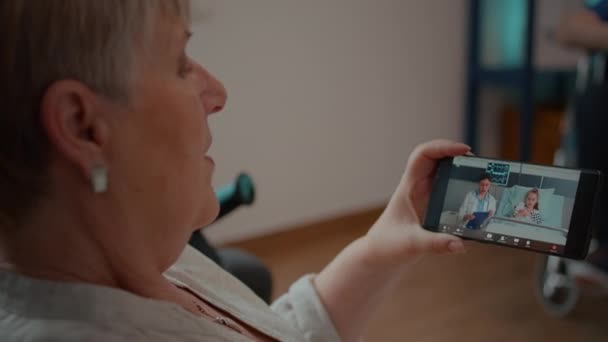 Persoană pensionară care utilizează teleconferință la distanță pentru a vorbi cu medicul și nepoata — Videoclip de stoc