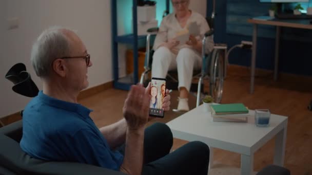 Uomo anziano che utilizza la videochiamata online per parlare con nipote e figlia — Video Stock