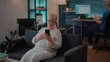 Üst düzey kadın akıllı telefondan video kameraya el sallıyor.